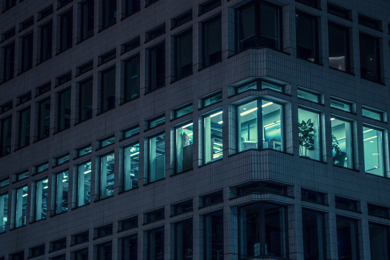 Illuminated office windows in a modern London building at night, capturing urban life.